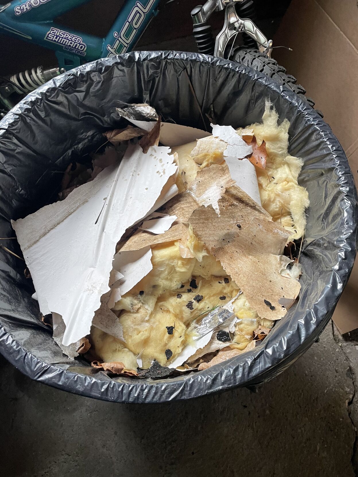 A trash can with debris and insulation in it